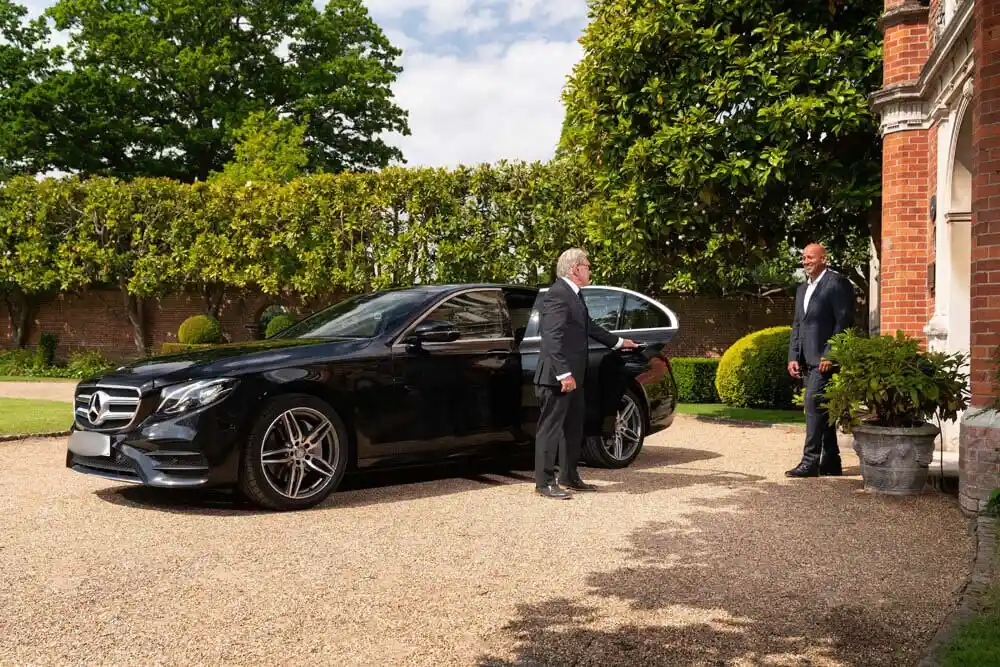 Business man getting picked up in a luxury for airport taxi transfers